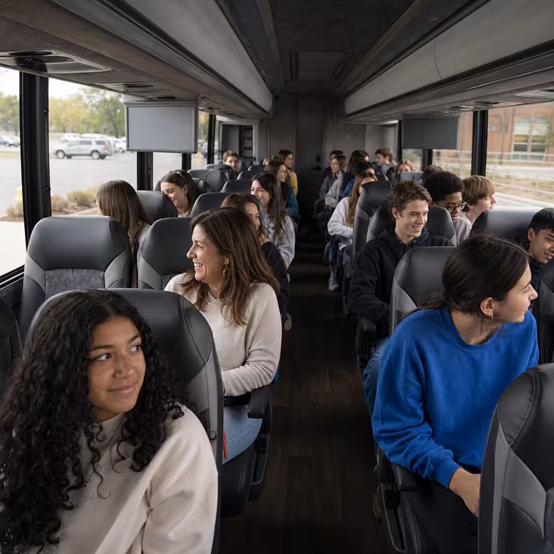 Group boarding a white charter bus for School Transportation transportation in Fort Wayne